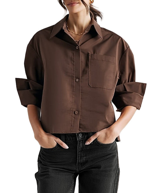 Woman wearing a brown shirt with rolled-up sleeves against a neutral background